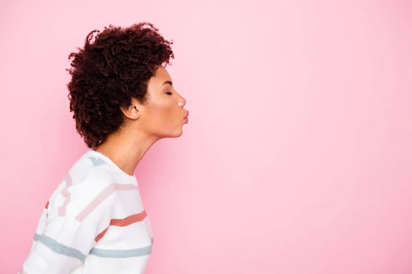 Foto de bonito agradável encantador mulher negra fascinante beijando espaço vazio perfil lateral vestindo suéter listrado branco isolado sobre fundo cor pastel rosa — Fotografia de Stock