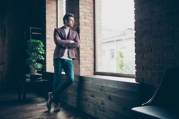 Full length photo of classy macho business guy with crossed arms looking window thoughtful wear stylish blazer turtleneck and jeans leaning wall modern office room — Stock Photo, Image