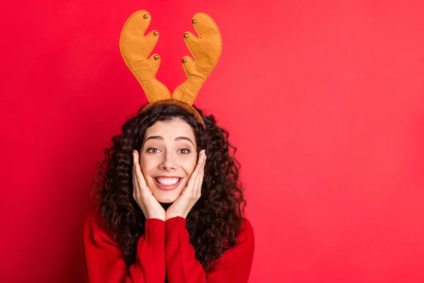 Фото смішної кучерявої леді, що тримає руки на вилицях збуджений очікування Санта-Клауса пізно на Різдвяний нічний одяг голови роги в'язаний пуловер ізольований червоний колір фону — стокове фото