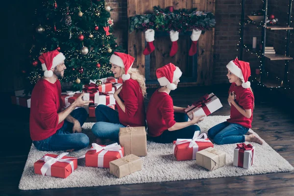 Büyük aile baba anne iki çocuk alışverişi x-mas hediyeler dekore çelenk ışıkları yeni yıl ağaç kapalı santa caps kırmızı kazak giymek yakınında rahat zemin oturan profil fotoğrafı — Stok fotoğraf