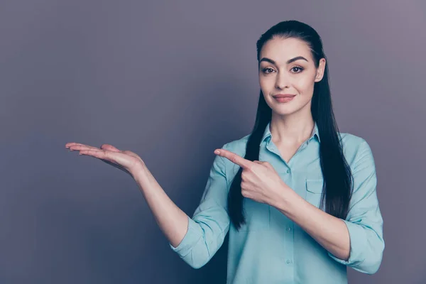 Foto de encantadora linda hermosa animada promotora confiada que muestra el objeto sostenido con su mano apuntando al espacio vacío en su palma aislada sobre el fondo de color gris — Foto de Stock