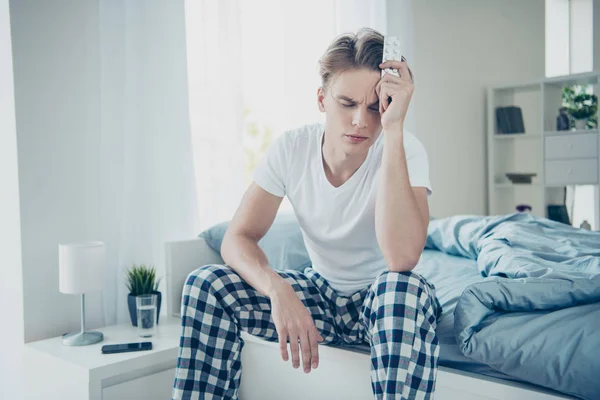 Porträt unglücklich traurigen männlichen Studenten haben Wochenenden leiden unter Kopfschmerzen Grippe halten Schmerzmittel Antibiotika fangen Virus Erkältung karierten Pyjama in Haus drinnen — Stockfoto