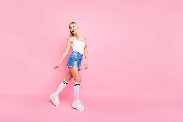 Ganzkörperfoto von flippigen schönen Mädchen haben Spaziergang tragen weiße Tank-Top Shorts Jeans isoliert über rosa Hintergrund — Stockfoto