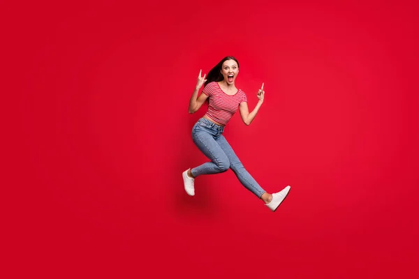 전체 몸길이의 브루 네트 사진붉은 배경에 고립되어 빠른 청바지를 입고 빠르게 움직이는 유행하는 여자 친구의 모습 — 스톡 사진