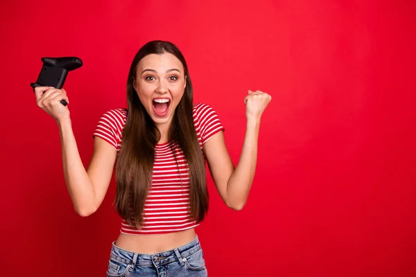 Foto de hermosa moda encantadora bonita morena linda linda novia encantadora adicta a los videojuegos con camiseta a rayas mientras está aislada con fondo rojo — Foto de Stock