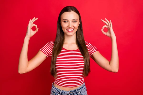 Foto de encantadora linda linda e interesante buena novia que muestra a todo el mundo ok signo mientras usa vaqueros denim aislado sobre fondo rojo — Foto de Stock