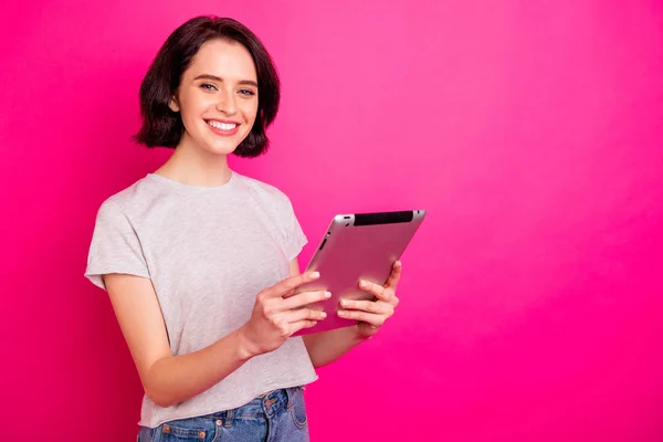 Portret van vrolijk opgewonden freelancer met behulp van tablet zoeken nieuws dragen witte t-shirt geïsoleerd over roze fuchsia achtergrond — Stockfoto