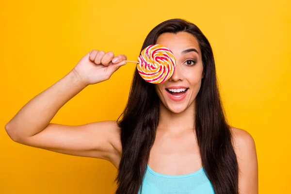 Photo of funny charming cute nice sweet millennial girl hiding her eye behind lollipop excited about taste fooling wearing turquoise tank-top isolated vibrant color background — Stock Photo, Image