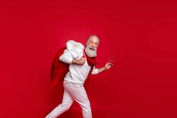 Hipster son sınıf öğrencisi havalı modern Noel Baba rolü hediyeler getiriyor moda örgüsü kıyafetler giyiyor izole edilmiş kırmızı arka plan — Stok fotoğraf