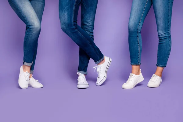 Foto de primer plano recortado de tres personas piernas con pantalones vaqueros azul oscuro pantalones de pie en el suelo aislado fondo violeta —  Fotos de Stock