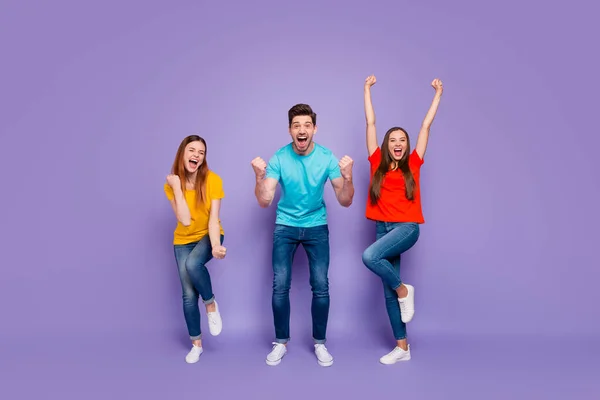 Volledige lengte body foto van vrolijke enthousiaste positieve gek met plezier triomf en geluk drie blij mensen gebaren handen omhoog vuisten omhoog geïsoleerde violette achtergrond — Stockfoto