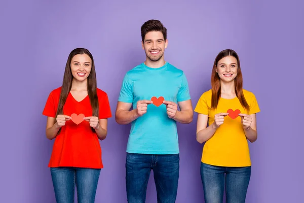 Foto de tres grupos de tenencias pequeña tarjeta de papel en las manos que muestra su amor aislado fondo violeta — Foto de Stock