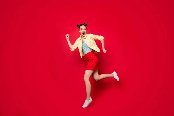 Фотографія повної довжини красивої стрибаючої леді, що працює швидко купуючи повсякденне вбрання ізольований червоний фон — стокове фото