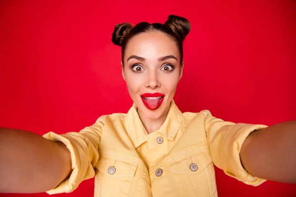 Coquettish lady making selfies sticking tongue out of mouth casual stylish outfit isolated red background — Stock Photo, Image