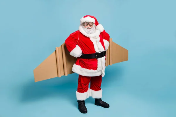 全身上下都是他那漂亮的胖胖的容貌，留着胡子的圣诞老人戴着飞机机翼，穿着保暖西服，手放在与蓝色绿松石色背景隔离的臀部上 — 图库照片