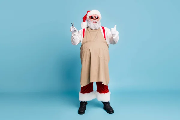 Full length body size view of his he nice atrakcyjny tłuszcz duży brzuch stylowy wesoły Santa gospodarstwa w rękach nożyczki pokazując kciuk odizolowany na jasny żywy połysk żywy niebieski turkusowy kolor — Zdjęcie stockowe