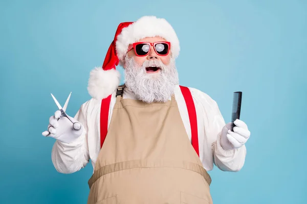 Close-up portrait of his he nice attractive cool stylish trendy cheerful cheery Santa holding in hands scissors brush isolated on bright vivid shine vibrant blue turquoise color background — Stock Photo, Image