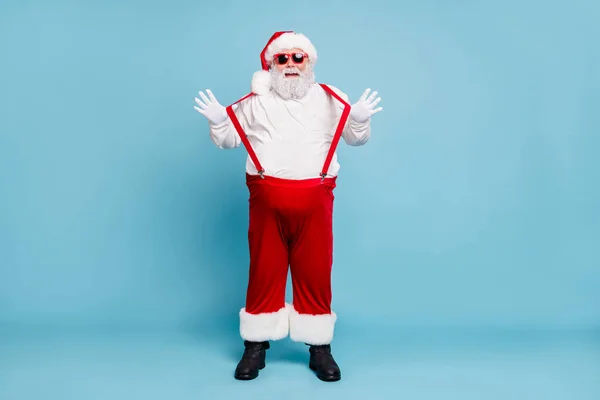 Foto de tamaño completo de la divertida grasa funky Santa Claus con gran abdomen del vientre se siente festivo disfrutar de alegre partido de año nuevo toque tirantes rojos aislados sobre fondo de color azul —  Fotos de Stock