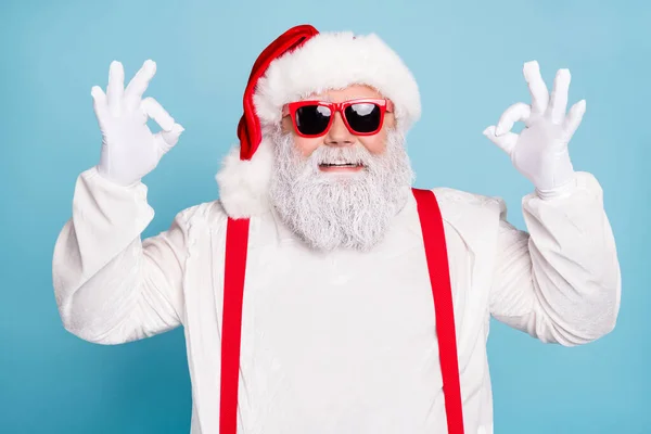 Close-up foto van grappige funky vet overgewicht hipster santa claus show ok ok goed teken raden winterseizoen winkelen verkopen dragen moderne brillen rood bretels geïsoleerd over blauwe kleur achtergrond — Stockfoto