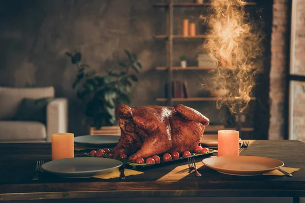 Foto de cerca de pavo asado al horno grande en medio de la mesa festiva platos vacíos y dos velas alrededor en la sala de estar sin personas en el interior — Foto de Stock