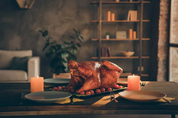 Foto de cerca de pavo asado al horno grande en medio de la mesa festiva platos vacíos y dos velas alrededor en la sala de estar sin personas en el interior — Foto de Stock