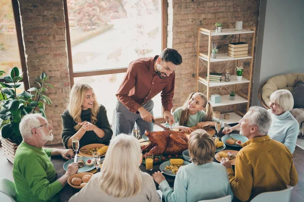 Büyük ailenin şölen sofrasında oturup yemek yerken çekilmiş bir fotoğraf. Kavrulmuş hindi, baba. Dilimler yapan, aç akrabalar. — Stok fotoğraf