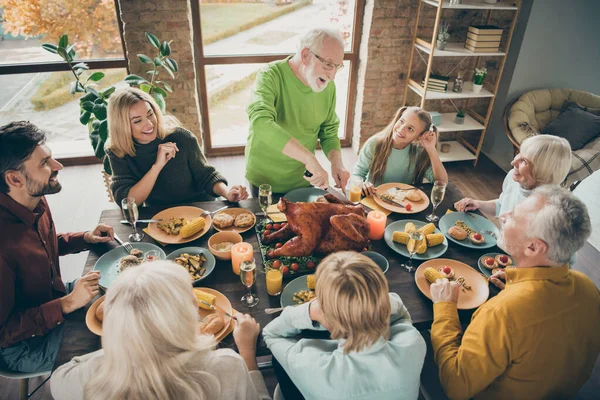 Photo of big family sit feast meals table around blessing roasted turkey eldest grandfather making slices hungry relatives waiting excited in living room indoors — Stock Photo, Image