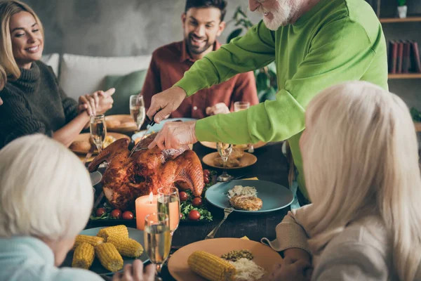 完全大家族の作物の写真は、室内のリビングルームで興奮待っているスライス空腹の親戚に肉を切断ロースト七面鳥の祖父の周りのごちそう料理テーブルに座る — ストック写真