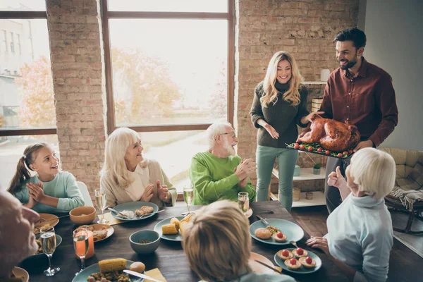 Wonderful housewife. Photo of full family sit feast dishes table meet big roasted turkey ovations clap arms multi-generation relatives event in living room indoors