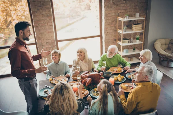 Photo of full big family gathering sit feast meals dinner table father guy telling thanksgiving pray toast multi-generation harmony in evening living room indoors — Stock Photo, Image