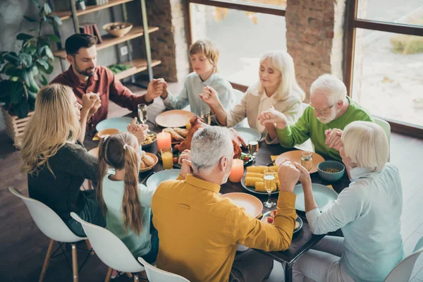 Retrato de agradável calma pacífica focada grande família completa irmão casais comendo almoço caseiro festa de mãos dadas rezando loft tijolo estilo industrial interior casa dentro de casa — Fotografia de Stock