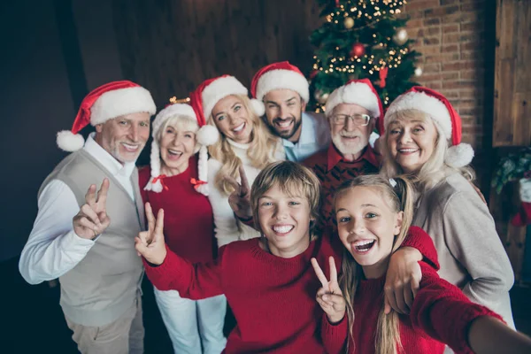 Neşeli, mutlu, aile babası, şapkalı abla şapkalı kız kardeşin portresi. Gelenek toplanıyor. Noel Baba, çatı katı endüstriyel tarzda bir evde V işareti gösteriyor. — Stok fotoğraf