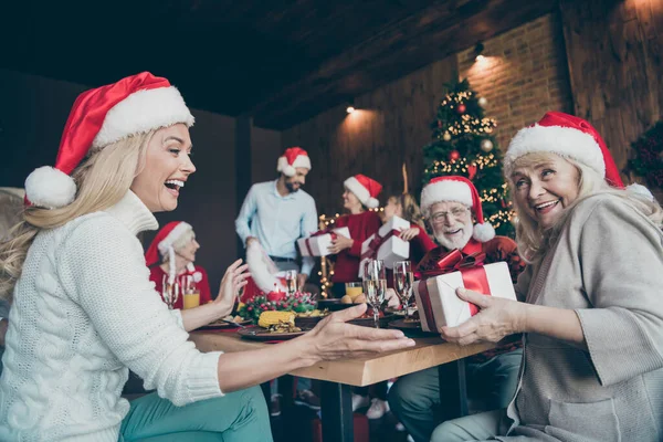 Närbild foto av familj återförening ha kul på god jul natt liten pojke son son barn tala far kvinna i Santa claus hatt ge presentbox önskan dröm till senior pensionär mor sitta bord i huset — Stockfoto