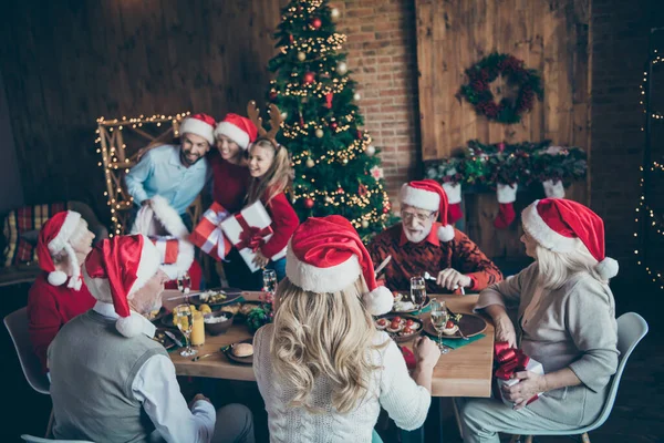 Grauhaarige Mann sprechen mit Enkelin sitzen Essen auf dem Tisch im Haus mit Weihnachten X-Heiligabend, wo Mann in Weihnachtsmannmütze kleinen Jungen Sohn Kind genießen Neujahr Zeit — Stockfoto