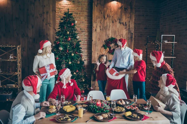 Foto von fröhlichen reifen kleinen Menschen Familie fröhlich Weihnachten sammeln Mann in Weihnachtsmann Hut offenen Sack Tasche geben Geschenk-Box Wunsch Überraschung sitzen um Esstisch im Haus mit Weihnachtsbaum — Stockfoto