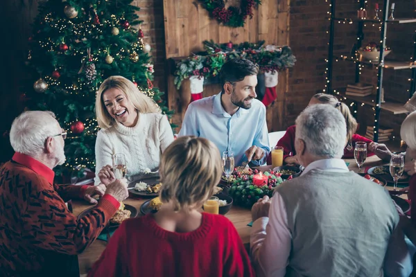 Фото полного семейного собрания, сидящего за обеденным столом, общающегося в чате на рождественскую вечеринку многопоколения в новогодней украшенной гостиной в помещении — стоковое фото