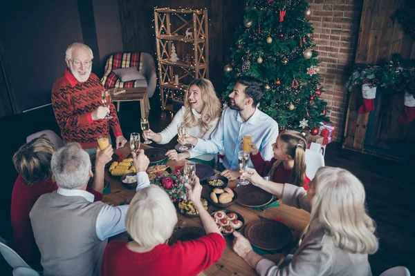 Yüksek açılı, neşeli, dolu bir ailenin kış bayramının tadını çıkarması. Aile geleneği. Brunch yemek, büyükbaba, köknar ağacının yanında kadeh kaldırmak. — Stok fotoğraf