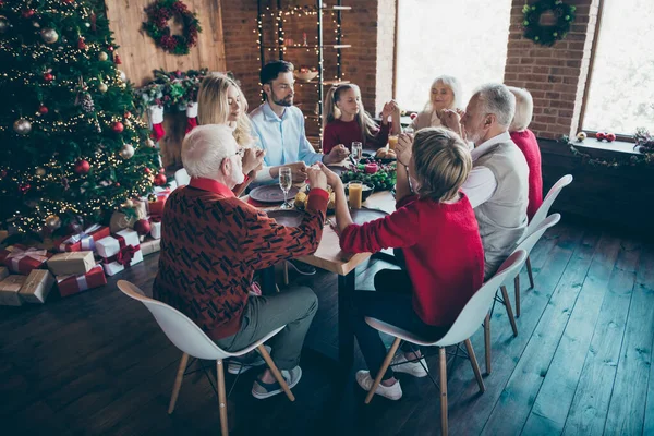 Nice friendly peaceful big full family son enjoying spending December eating homemade lunch holding hands praying in modern industrial loft brick style interior decorated house indoors