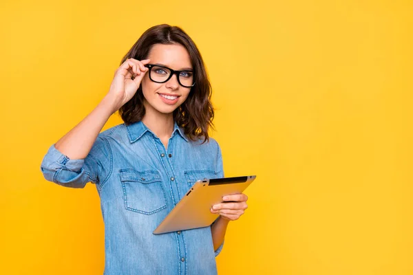 Porträtt av säker cool expert frilansare smm i snygga glasögon använda hennes tablett förbereda arbete projekt bära jeans kläder isolerad över gul färg bakgrund — Stockfoto