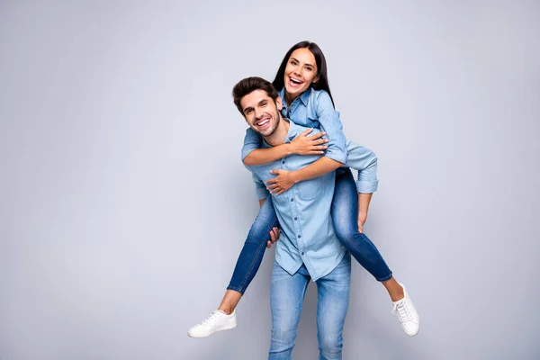 Фото смішного хлопця і леді, що тримає свинарник, граючи в розважальну гру, радісно носить повсякденний одяг з джинсами ізольований сірий кольоровий фон — стокове фото