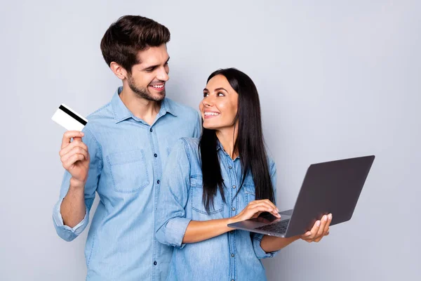 Photo of stylish trendy couple of two people business family with him holding credit card and her laptop developing social media pages isolated grey color background — Stock Photo, Image