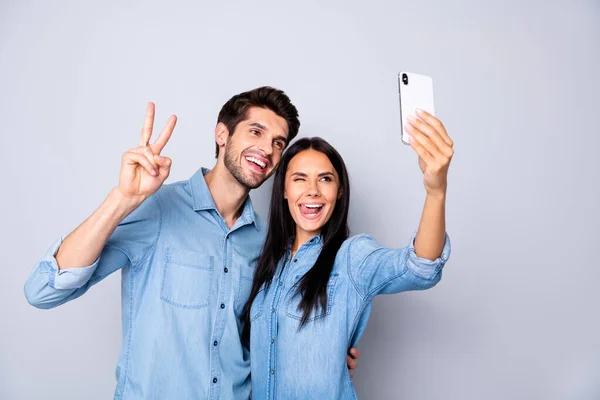 素敵な魅力的な陽気なカップルの肖像画手の携帯電話で保持カジュアルシャツを身に着けている自撮り旅行ブログを示すv-signは、ライトホワイトグレーのパステルカラーの背景に隔離された — ストック写真