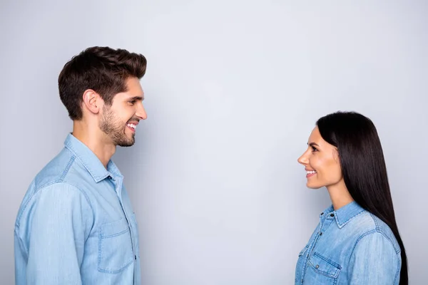 Boczne zdjęcie profilowe wesołej uroczej pary dwóch osób razem nawiązujących kontakt wzrokowy rozmawiających ze sobą w dżinsach dżinsy odizolowany szary kolor tła — Zdjęcie stockowe