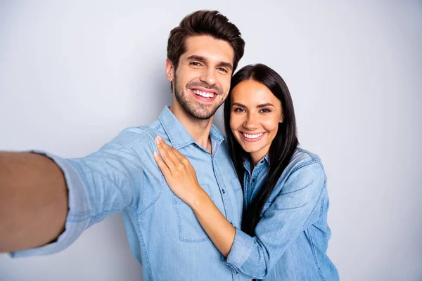 Автопортрет красивой очаровательной очаровательной пары, одетой в джинсовые рубашки, улыбающейся зубочисткой, делающей селфи изолированным на сером фоне — стоковое фото