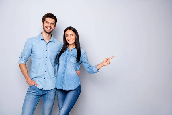 Photo of cheerful trendy charming brown haired nice cute couple of two people pointing at emptiness away wearing jeans denim jackets isolated over grey color white background — Stock Photo, Image