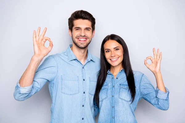 Photo of cheerful charming cute trendy stylish couple of two people standing together wearing jackets of denim showing you ok sign isolated over grey color background — Stock Photo, Image