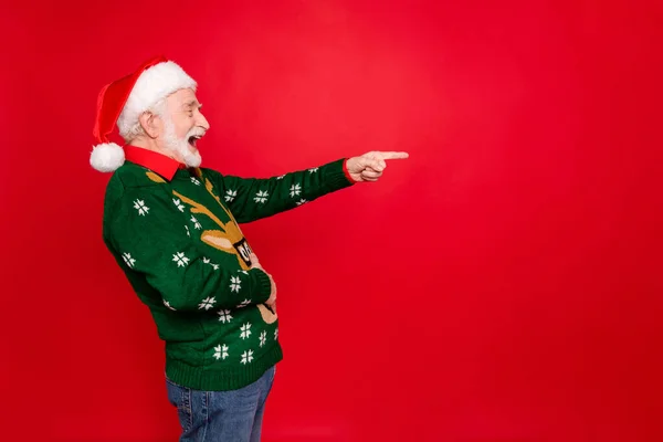Profile photo of santa man indicating finger to empty space laughing of loser people holding hand on belly wear x-mas ugly ornament sweater cap isolated red background — Stock Photo, Image