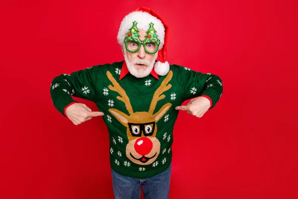 Foto av Santa tittar på otroligt låga julen shopping priser indikerar fingrar på billiga jumper bär x-mas träd form specs ful prydnad tröja isolerad röd bakgrund — Stockfoto