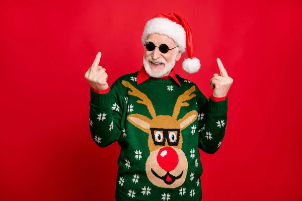 Fuck haters show sign. Portrait crazy grey white hair naughty mad old man in black spectacles santa claus cap laugh on x-mas celebration time wear antler decor sweater isolated red color background — Stock Photo, Image