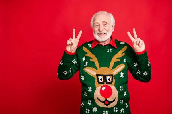 Portrait of positive cheerful grey hair old man enjoy theme noel x-mas time party make v-signs wear reindeer pattern design tradition clothes isolated over red color background — Stock Photo, Image